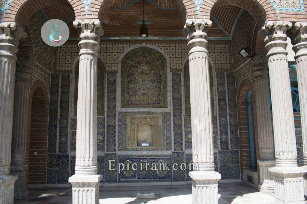 columns in front of decorated wall by blue tiles in moghadam museum in tehran
