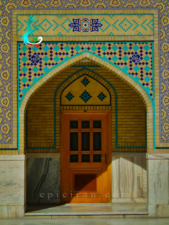 wooden door inside of an arch decorated with islamic tiles in pir palandouz in mashhad