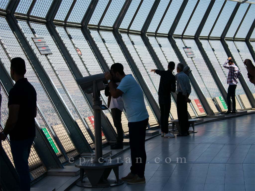 a man who watch landscapes by a huge Binocular in the top of milad tower in tehran