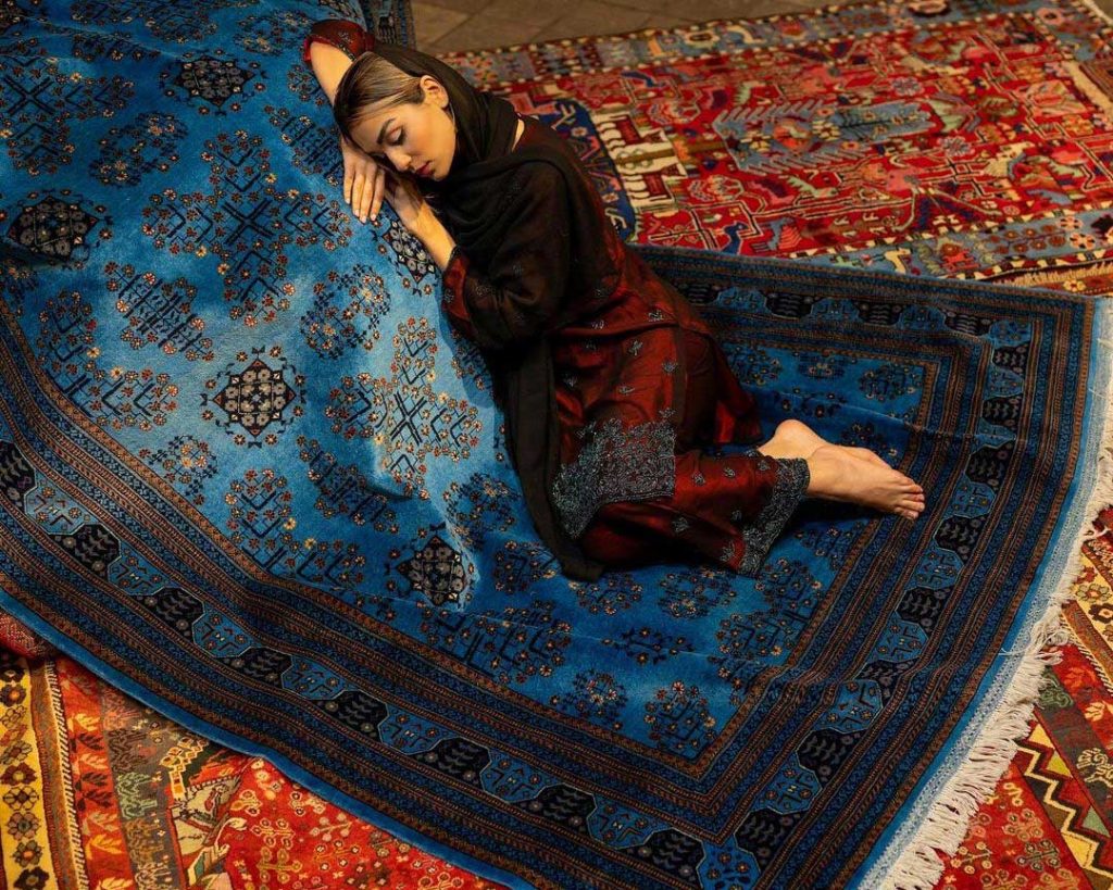 an iranian girl in red clothes is sleeping on a Blue persian rug