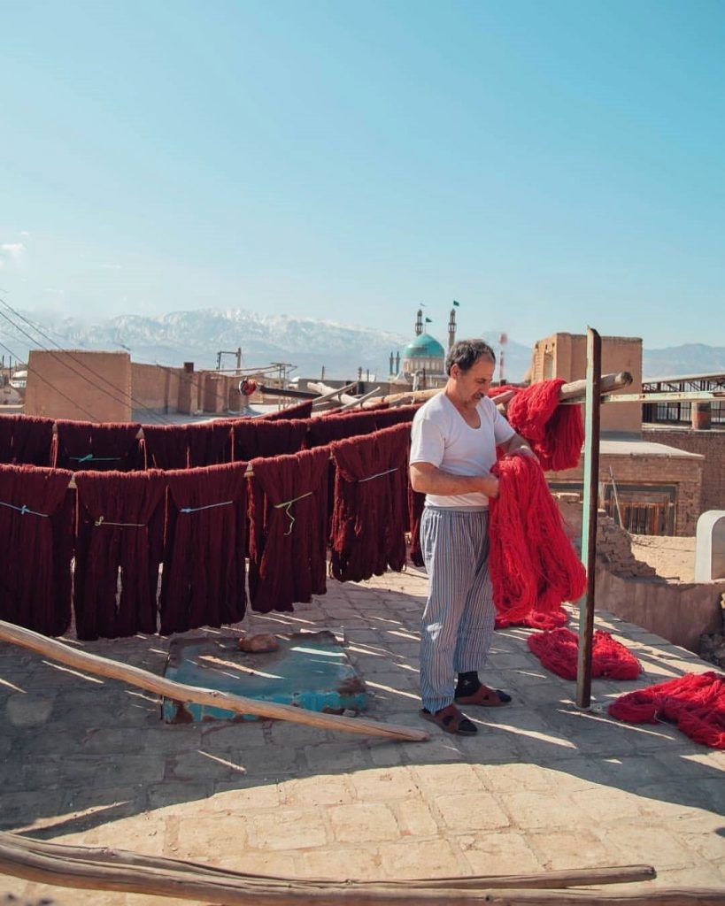 a man pijamas who maintain and obtain red threads for weaving as colors in persian carpets