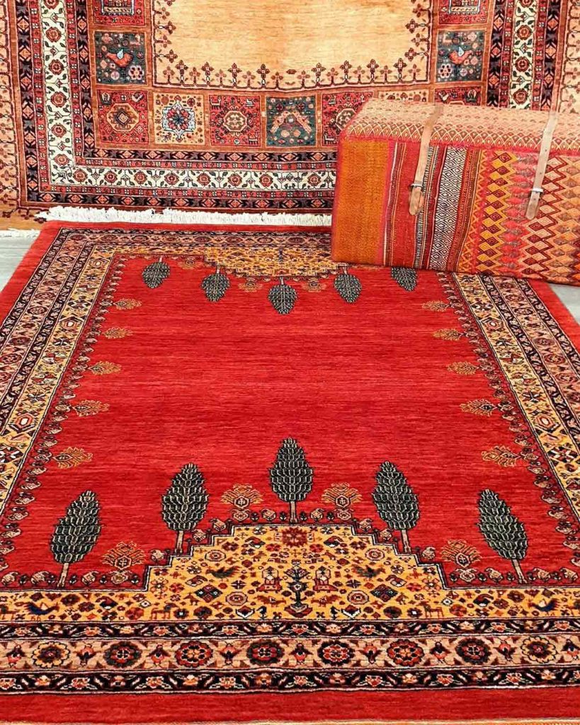 a red persian rug with trees pattern spread on the floor