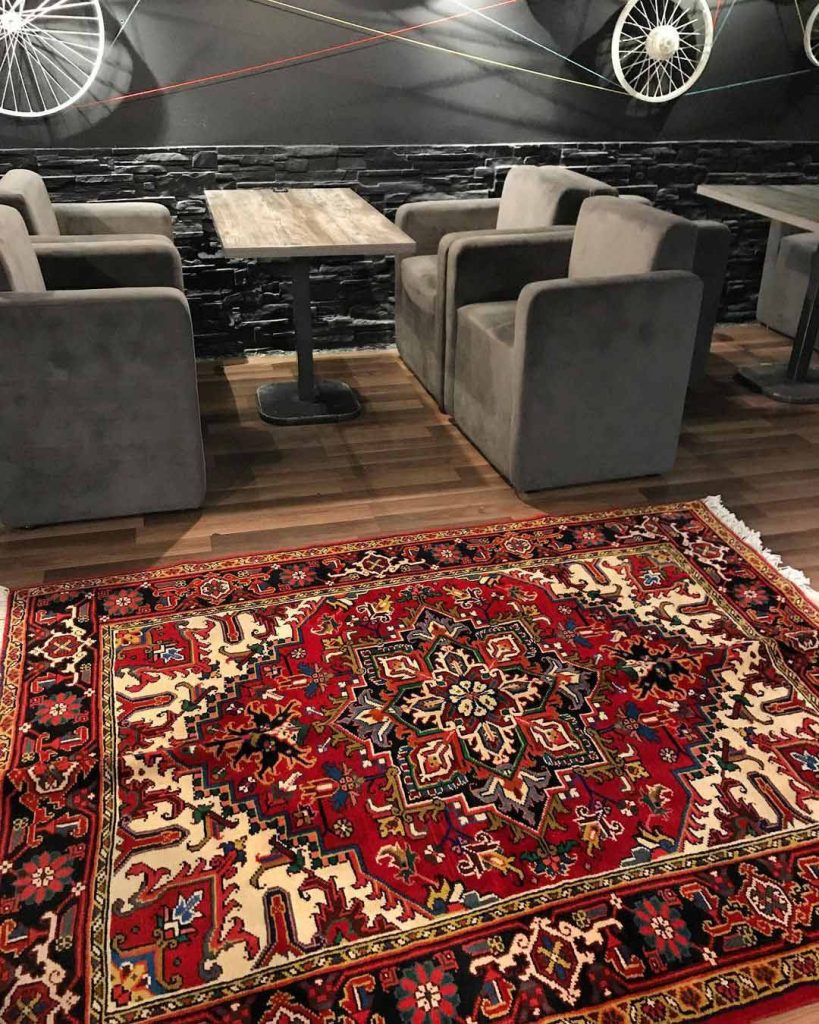 a red persian rug next to grey furniture and grey decoration