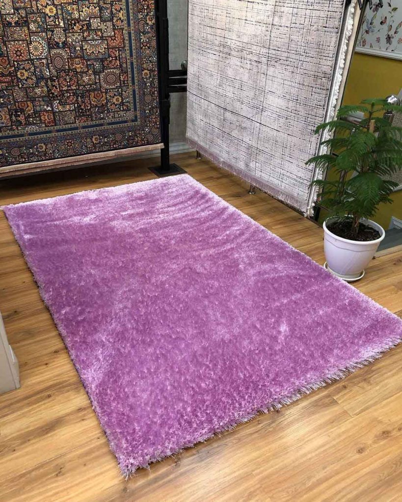 a pink persian rug spread on the floor next to two hanged rug
