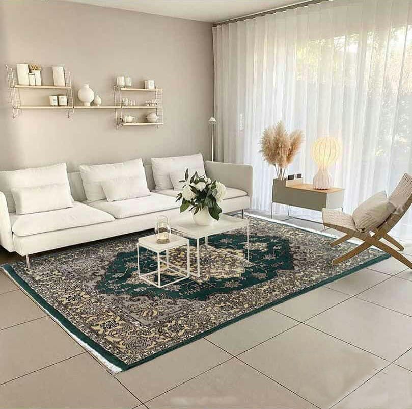 an area green persian rug in a living room arranged by white furnitures